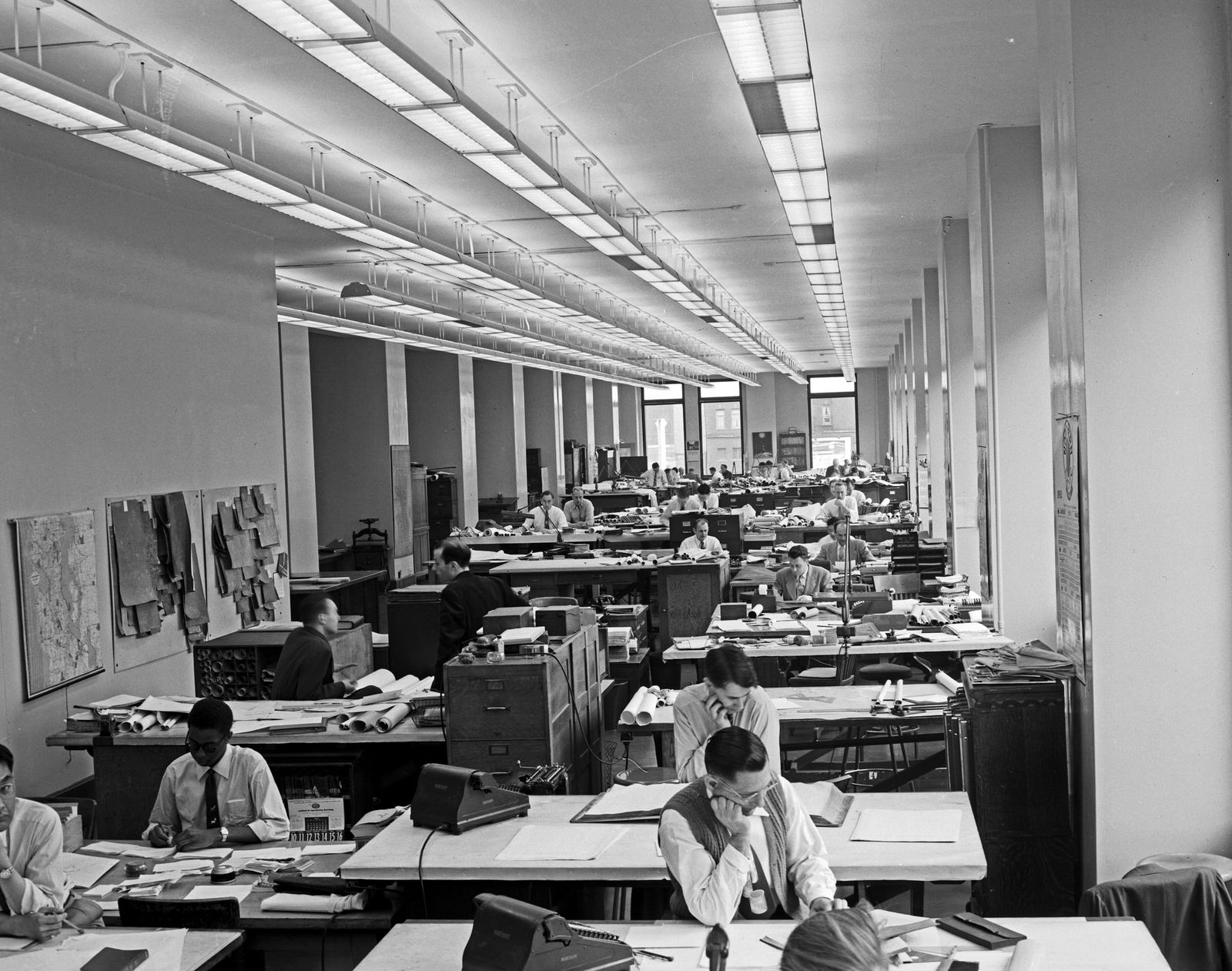 Oficina de ingeniería y dibujo técnico con largas filas de escritorios y personal trabajando, 1953